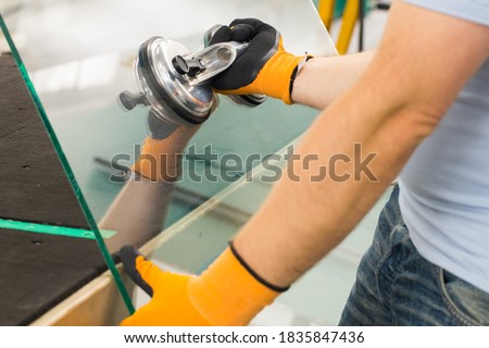 The Glazier uses a sucker for windows. Glass making workshop, The man lifts the pane of thick glass on the table with the help of specialized tools