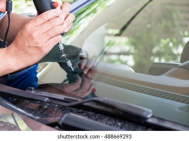 Glazier using tools repairing to fix crack windshield