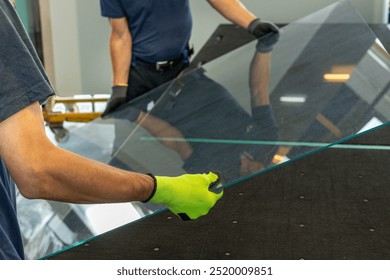 Glaziers place a large pane of glass on a table in the glassworks