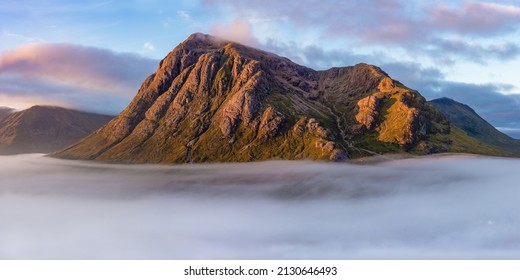 Glencoe, Scotland – September 7, 2019: Colorful, epic panoramic view of mountains at sunrise above a dramatic cloud inversion in Glencoe, Scotland.  - Shutterstock ID 2130646493