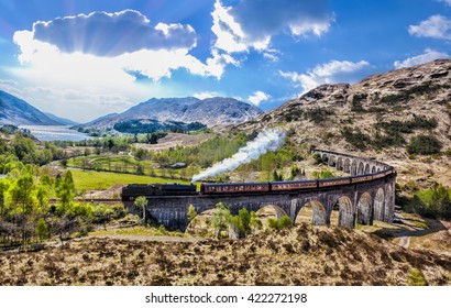 Glenfinnan Railway Viaduct in Scotland with the Jacobite steam train against sunset over lake - Powered by Shutterstock