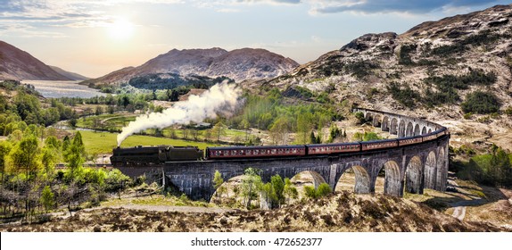 Glenfinnan Railway Viaduct in Scotland with the Jacobite steam train against sunset over lake - Powered by Shutterstock