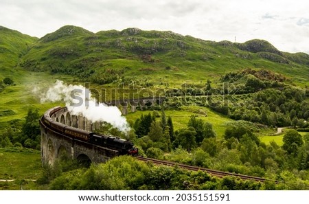 Glenfinnan Viaduct, Scotland. Travel tourist destination in Europe. Old historical steam train riding on film scene famous Harry Potter viaduct bridge. Highlands, mountains, outdoor background.