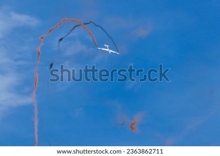 Glider plane maneuvering on blue sky with smoking from wings. Aviation, leisure sport background