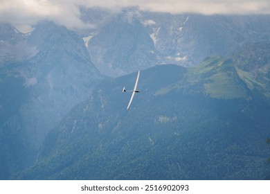 A glider plane soaring through the sky with clouds in the background, high above the Bavarian Alps. - Powered by Shutterstock