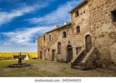 A glimpse of the ancient medieval village of Montecalvello, Viterbo, Italy. The internal courtyard of the castle with the ancient stone and brick buildings and the fountain in the center. - Powered by Shutterstock