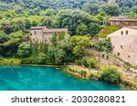 A glimpse of the small village of Stifone, on the Nera river. Umbria, Terni, Italy. The walls of stones and bricks. The bridge over the river with clear blue waters. Tourists stroll through the alleys