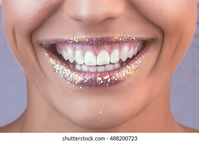 Glitter lips. Perfect teeth. Close-up shot of female laugh lips with bright lipstick in retro style colors.