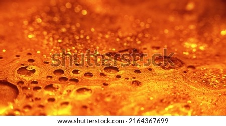 Glitter paint flow. Molten gold texture. Floating ink. Defocused yellow orange sparkling fluid motion. Abstract art background shot on RED Cinema camera.