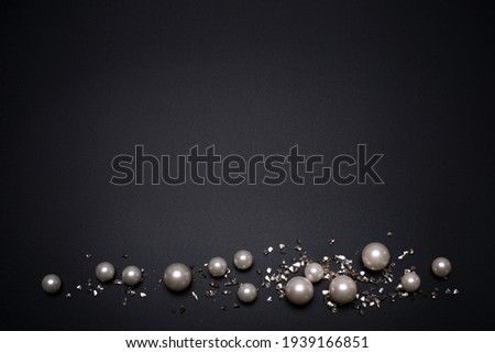 Glitter and pearls on the black background, with free space for text.