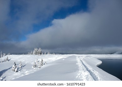 Glittering Sparkle Deep Powder Snow With One Backcountry Skiing Track Along Streuboeden Reservoir. Snow Covered Spruce And Fir Trees. Sunshine But Dark Clouds Coming Closer.