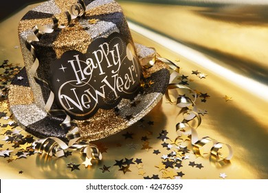 Glittery new year's hat with streamers and confetti shot on gold metallic background