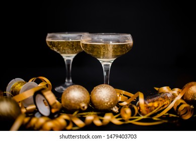 Gllasses Of Champagne On Black Stylish Background With Place For Text. Festive Concept.Golden Stylish Decoration On Black Background.  Sticky Tape, Christmas Balls, Golden Ribbon