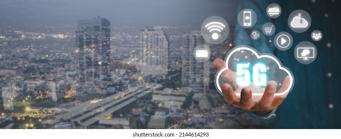 Global Communication Network Concept, Person Hand Holding 5G Icon On Virtual Screen With City Scape Background, World Wide Business, High-speed Mobile Internet, New Generation Networks. Mixed Media.