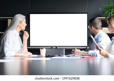 Global corporation online video chat business webinar in meeting room with multiethnic diverse colleagues in office watching big empty blank white screen monitor. Business technologies concept. - Powered by Shutterstock