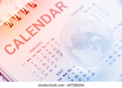Global date and time or time zone concept : Etched world map on a surface of a clear crystal globe with longitude and latitude lines, put over a mulberry paper calendar with North pole facing up.