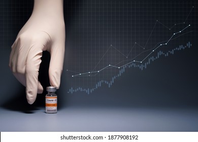 Global Economy Recovery After Covid 19 Vaccination Success Concept. Hands Of A Researcher In Medical Gloves Pick Up A Coronavirus Vaccine Vial With Stock Index Chart Rising Up In The Background.