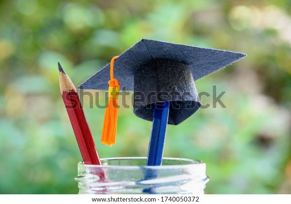 Global education success / graduate study aborad\
program concept : Black graduation cap or a mortarboard, blue and\
red pencils in a bottle, depicts achievement in higher mba learning\
course in academy