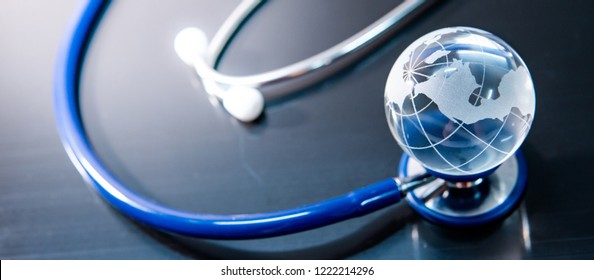 Global healthcare concept. World globe crystal glass on blue stethoscope on glossy desk. Health and medical science. Worldwide wellness business