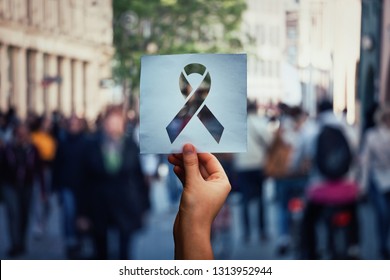 Global issue stop AIDS as hand holding a paper sheet with HIV red ribbon symbol over crowded street background. Fight against cancer concept, substance abuse and anorexia awareness. - Shutterstock ID 1313952944