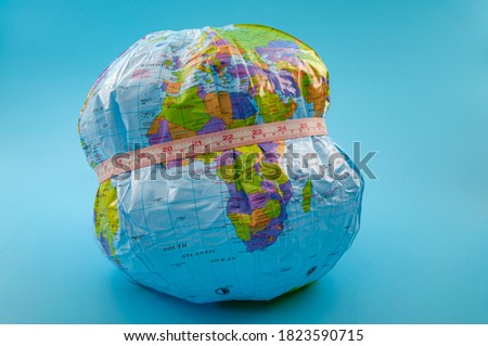 Global obesity epidemic crisis affecting increasing numbers of earth population and chronic health condition concept with globe and measuring tape isolated on blue background