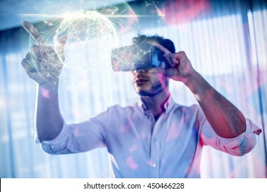 Global technology background in green against businessman using an oculus