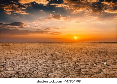 Global worming concept - cracked scorched earth soil drought desert landscape dramatic sunset