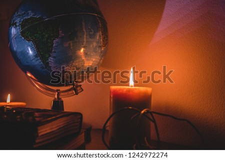 globe in candles light background on a wooden surface with stones and ancient books