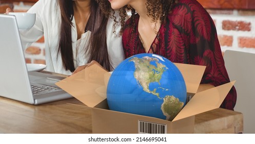 Globe in delivery box against mid section of two women using laptop in a cafe. logistics and transportation business concept - Powered by Shutterstock