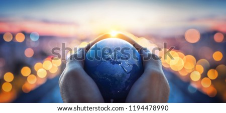 The globe Earth in the hands of man against the night city. Concept on business, politics, ecology and media. Earth day abstract background. Elements of this image furnished by NASA