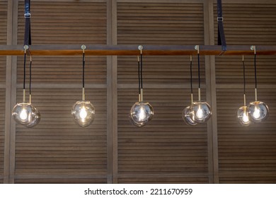 Globe Glass Pendant Light Chandelier In Antique Brass Finish With Wooden Cladding Background, Selective Focus , Front View