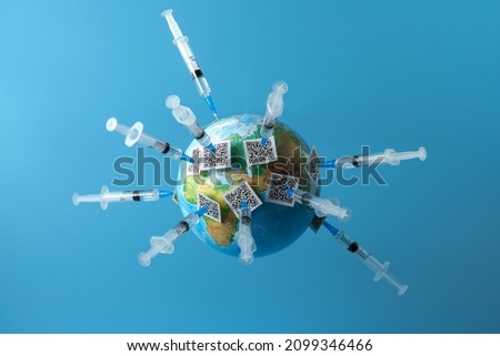 A globe on a blue background with many vaccination certificates on the needles of syringes. Copy space.                             