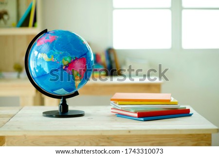 Globe on desk.Pinewood table.Shelves with colorful books.Background.Planet Earth and map.Geography lesson.
