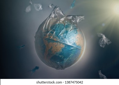 Globe Of Planet Earth Dressed In A Garbage Plastic Bag. Fly Around The Pieces Of Broken Plastic. The Concept Of Land Pollution And Ecological Imbalance.