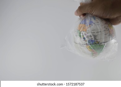 Globe is wrapped in plastic on hand of human . Show the environmental problem with the pollution of the earth with plastic and warming due to greenhouse effect. from plastic garbage in ocean or sea.