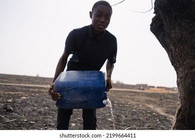 Gloomy And Blurry Image Of A Young African Man With A Can Of Water, Irrigating A Dried Up Field; Concept Of Hopelessness Of Third World People To Cope With Climate Catastrophe And Drought