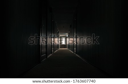 gloomy dark corridor with closed doors of an empty hotel without people during quarantine