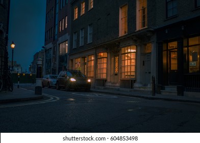 Gloomy Street At Night In London, UK With Car Headlights Creating A Perilous And Haunting Atmosphere