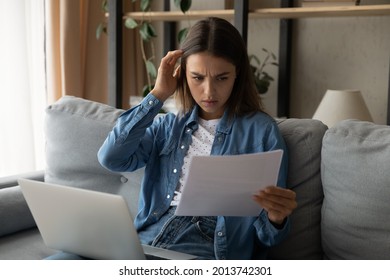 Gloomy Young Woman Sit Indoor With Laptop On Laps Hold Papers Read Document Check Domestic Bills Pay Taxes, Has Financial Problem, Learn Budget Balance Statement, Feels Worried About Loan Debt Penalty