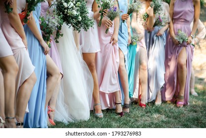 Glorious bridesmaids in pink, blue dresses holding beautiful bunch of flowers.