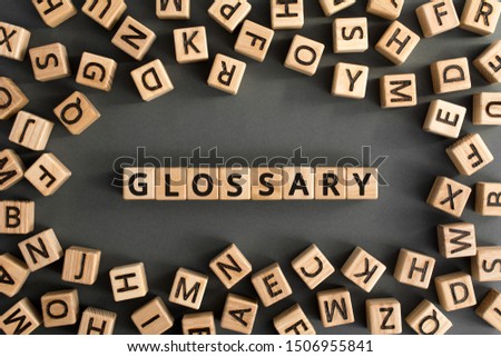 Glossary - word from wooden blocks with letters, alphabetical list with words meanings dictionary glossary  concept, random letters around, top view on grey background