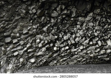 Glossy basalt column wall inside Halsanefshellir cave on Reynisfjara beach, Iceland