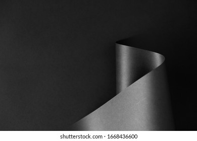 Glossy Black Monochrome Paper Wave On Dark Background. Geometrical Minimalist Style Backdrop.