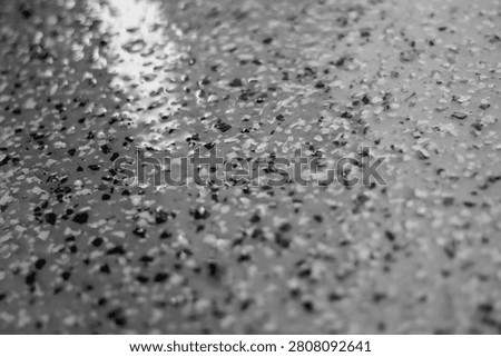 Glossy close-up of a gray flake epoxy floor coating 10 years after installation during a seasonal clean. a damp surface drying. abstract background