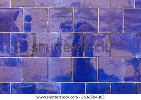 Glossy deep blue rectangular ceramic tiles arranged in a brick pattern on a wall