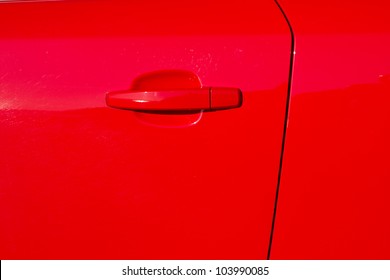 A Glossy Red Painted Car Door With Door Edge And A Handle.