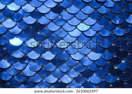 A glossy texture of blue sequins creating a fish scale effect. Ideal for background designs and fashion collections. macro texture fabric sequins