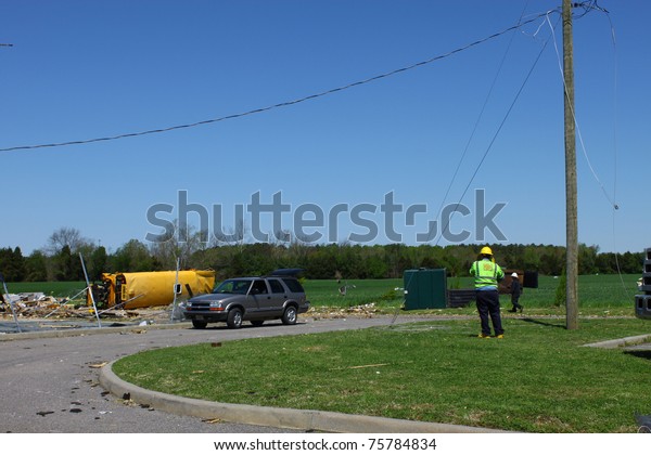 GLOUCESTER, VIRGINIA -\
APRIL 16: An unidentified electrician prepares to repair power\
lines on April. 16, 2011 after a tornado damaged lines and property\
in Gloucester, Virginia. An overturned and destroyed school bus\
lies in the\
distance.