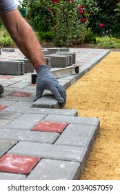 The gloved craftsman puts the paving stones