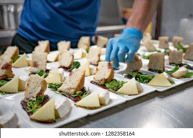 Gloved Hand Garnishing Gourmet Cheese Plates With Bread And Fruit Spread For Catering